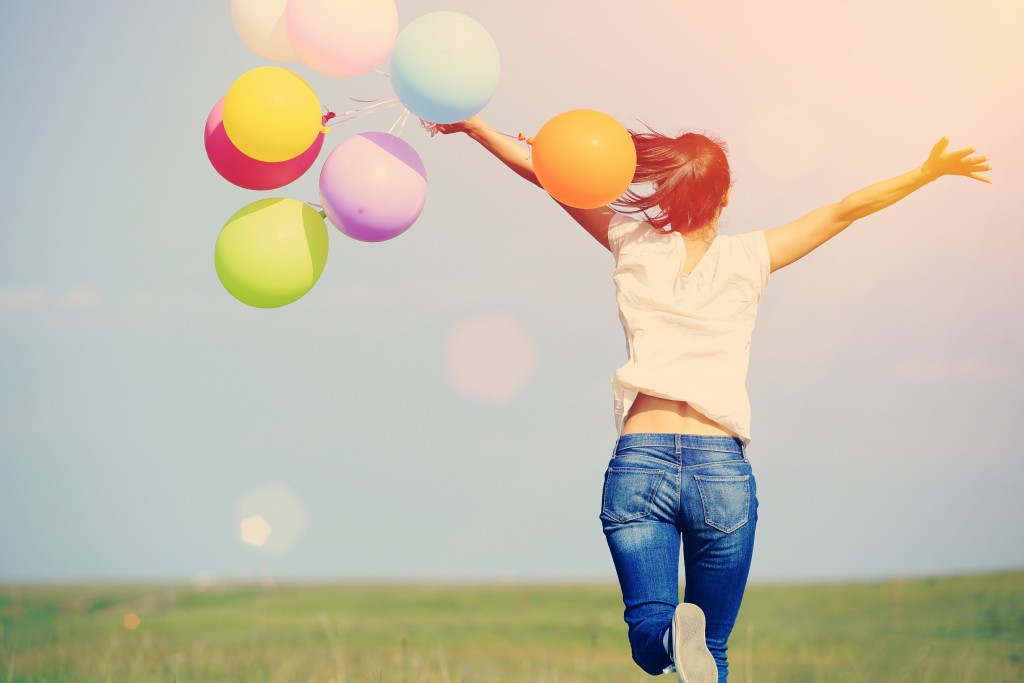 young asian woman on green grassland with colored balloons